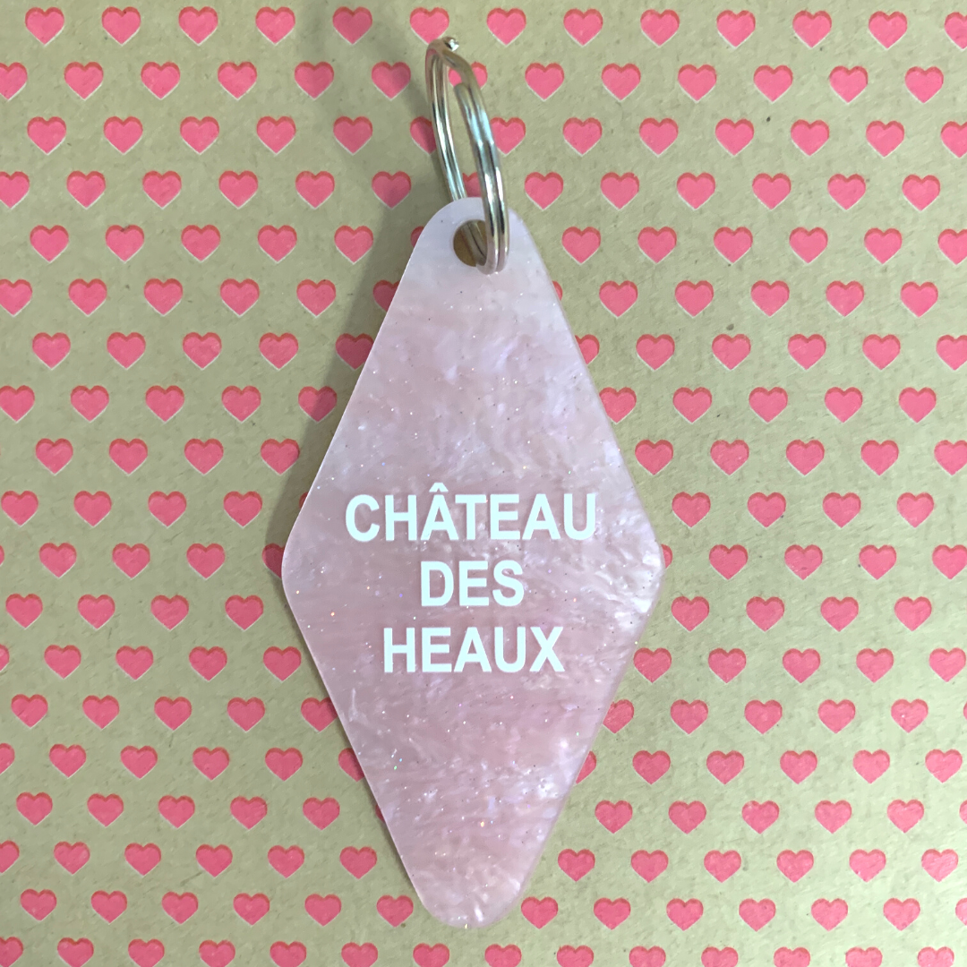 Chateau Des Heaux Motel Style Keychain in Crystal Pink with white lettering, featuring a split ring for key attachment.