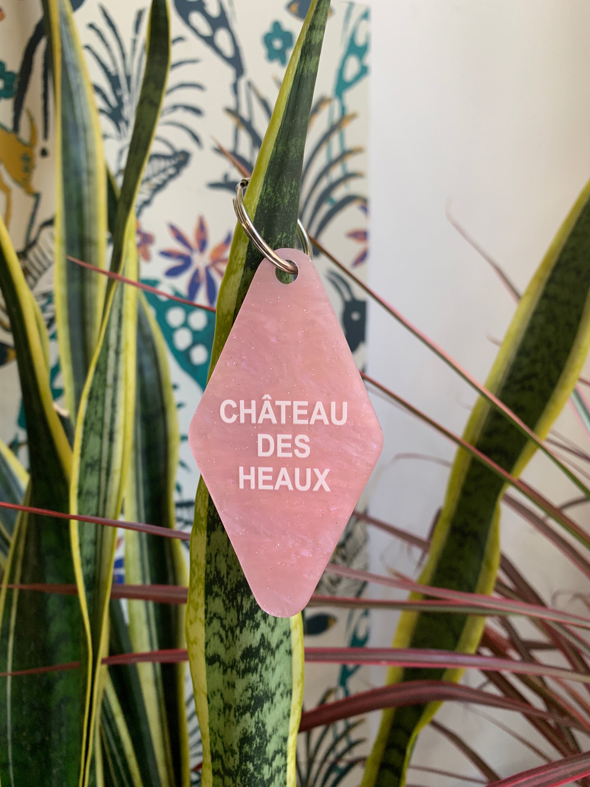 Chateau Des Heaux Motel Style Keychain in Crystal Pink with white lettering, featuring a split ring for key attachment.
