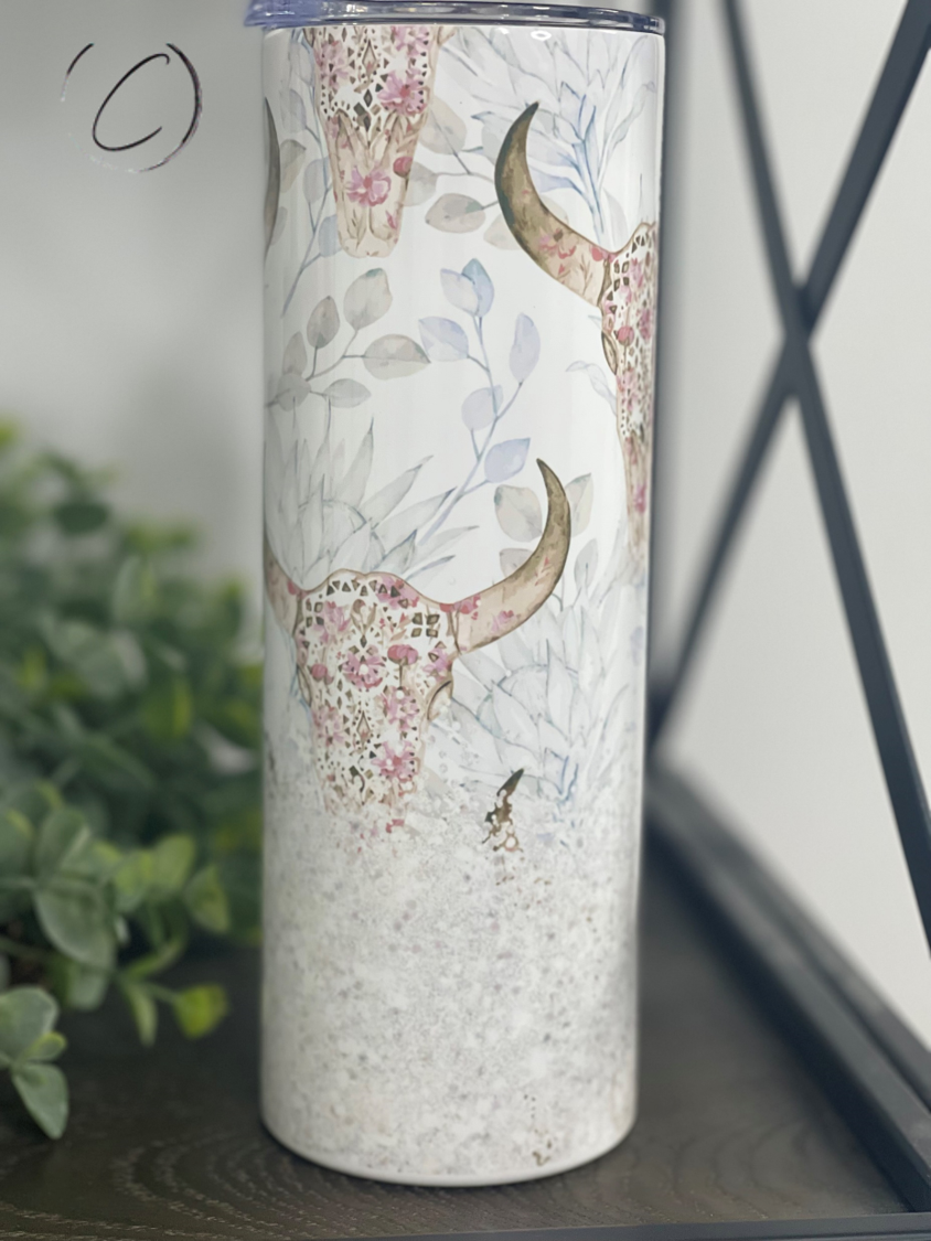 A stylish 20oz skinny tumbler featuring a floral bull skull design, perfect for hot and cold beverages.