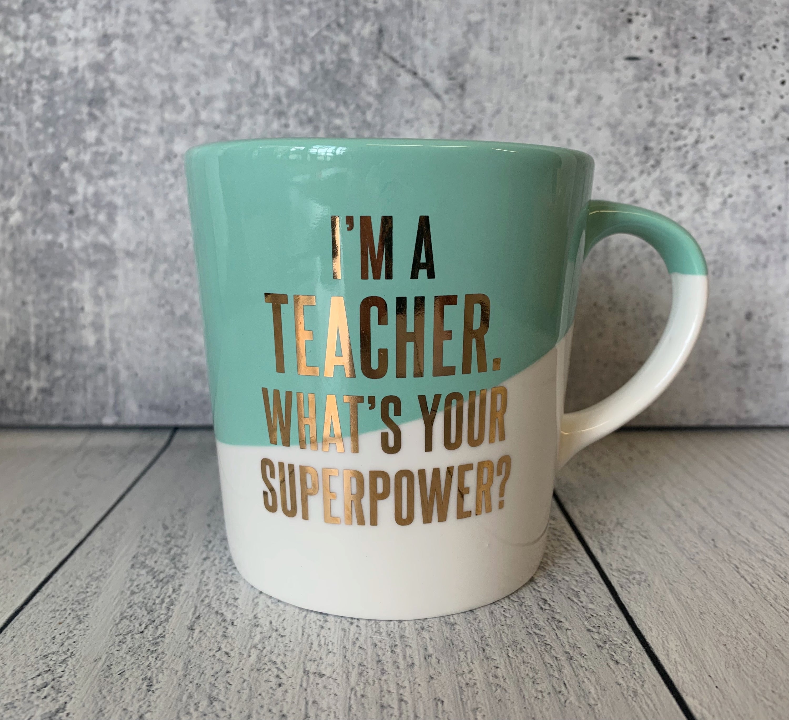 Ceramic coffee mug with blue slanted dip and gold lettering saying 'I'm a Teacher. What's Your Superpower?'