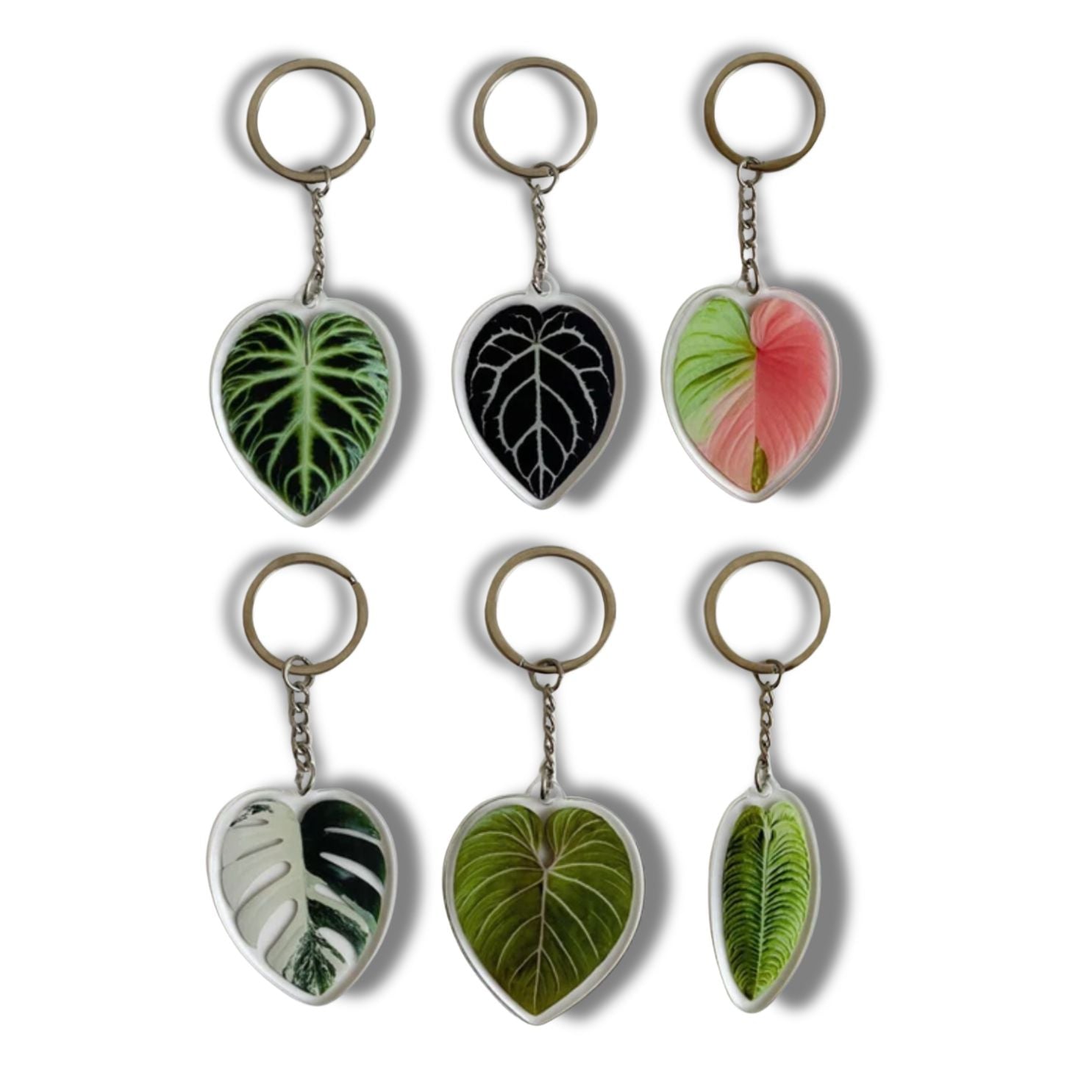 A collection of seven illustrated leaf acrylic keychains displayed on a clear background, showcasing vibrant colors and double-sided designs.