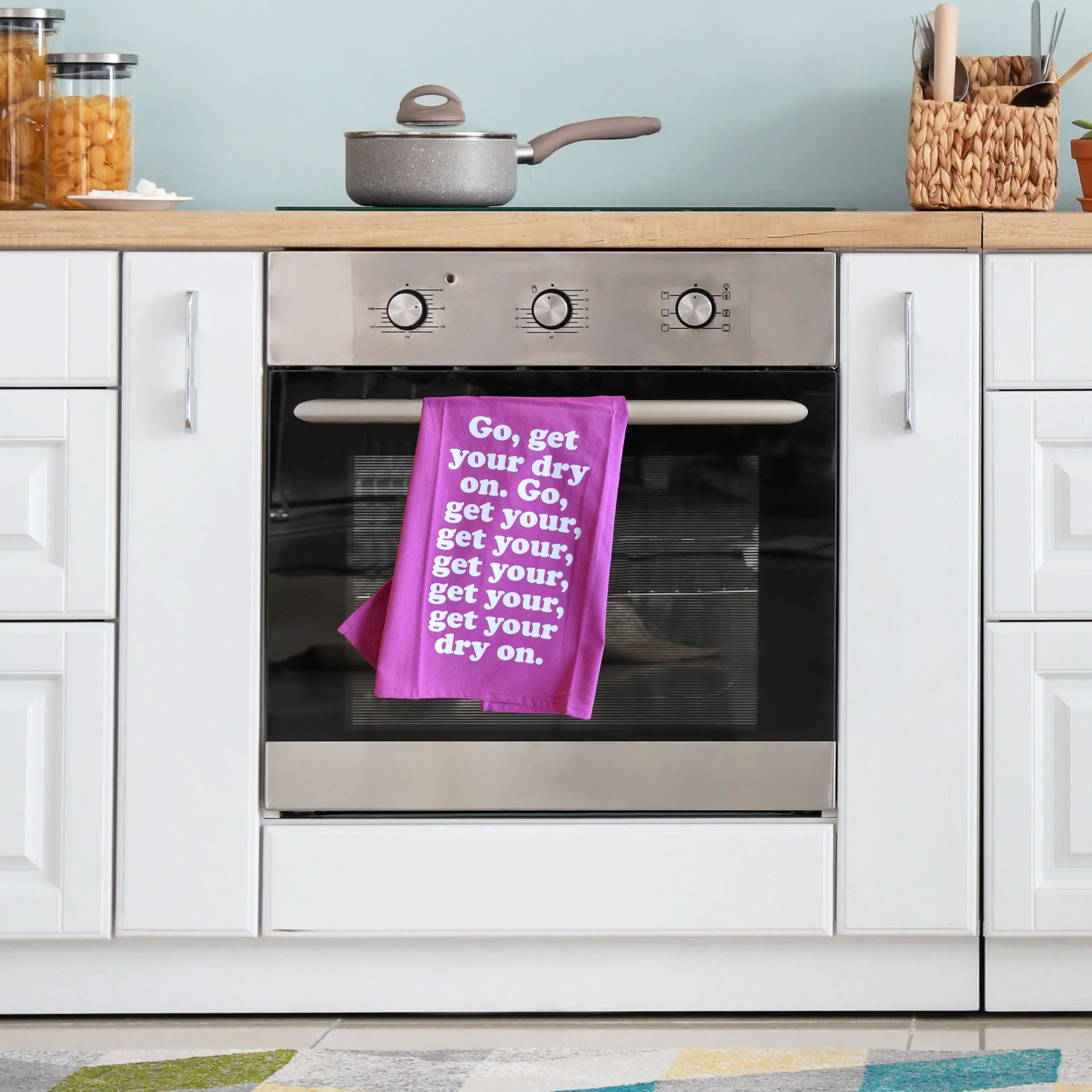 Missy Elliott-inspired cotton tea towel with the phrase 'Go, get your dry on' screen-printed in vibrant colors, hanging on a kitchen rack.