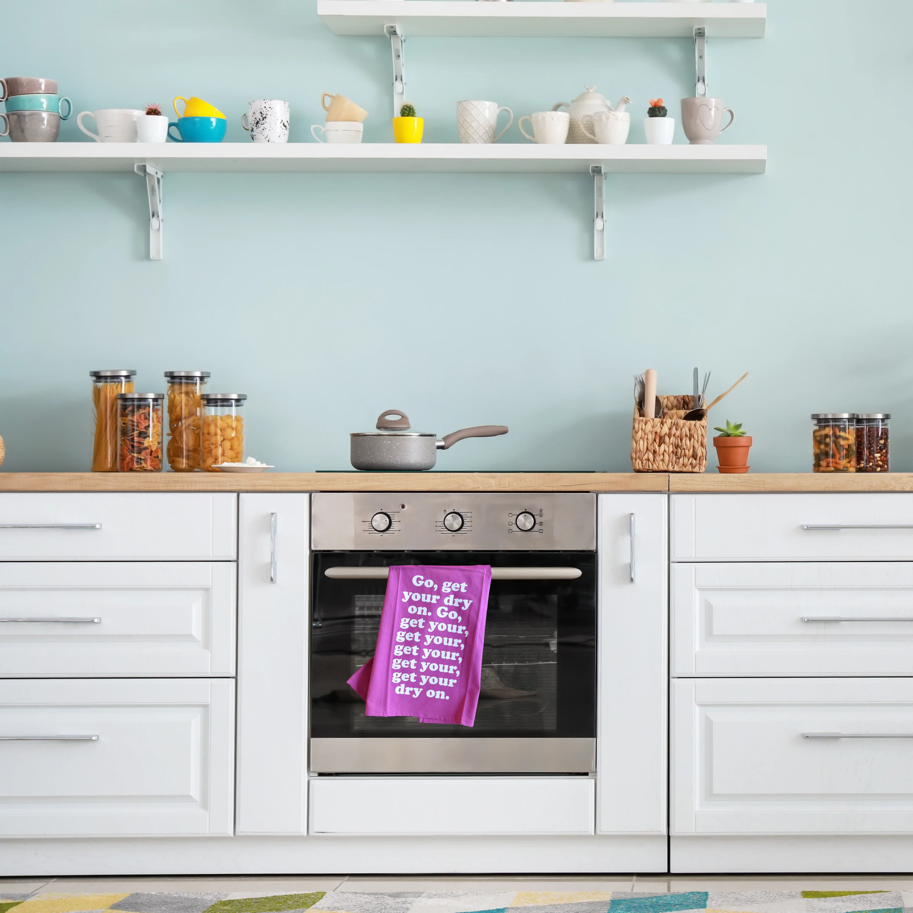 Missy Elliott-inspired cotton tea towel with the phrase 'Go, get your dry on' screen-printed in vibrant colors, hanging on a kitchen rack.