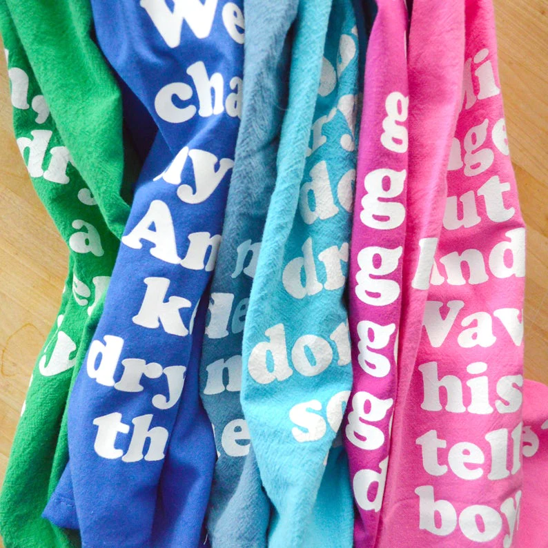 Missy Elliott-inspired cotton tea towel with the phrase 'Go, get your dry on' screen-printed in vibrant colors, hanging on a kitchen rack.