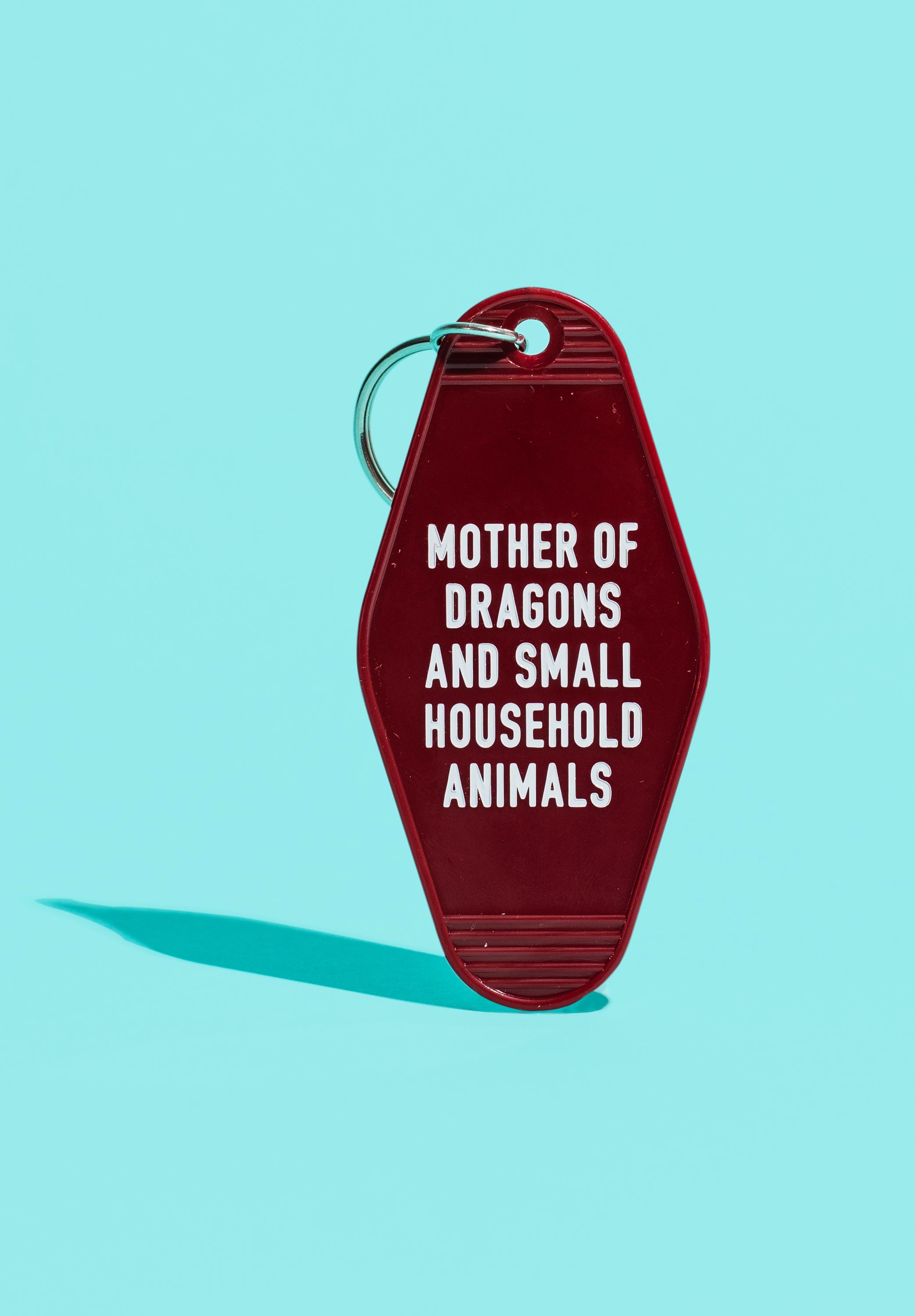 Dark red motel style keychain with white lettering reading 'MOTHER OF DRAGONS AND SMALL HOUSEHOLD ANIMALS', featuring a split ring.