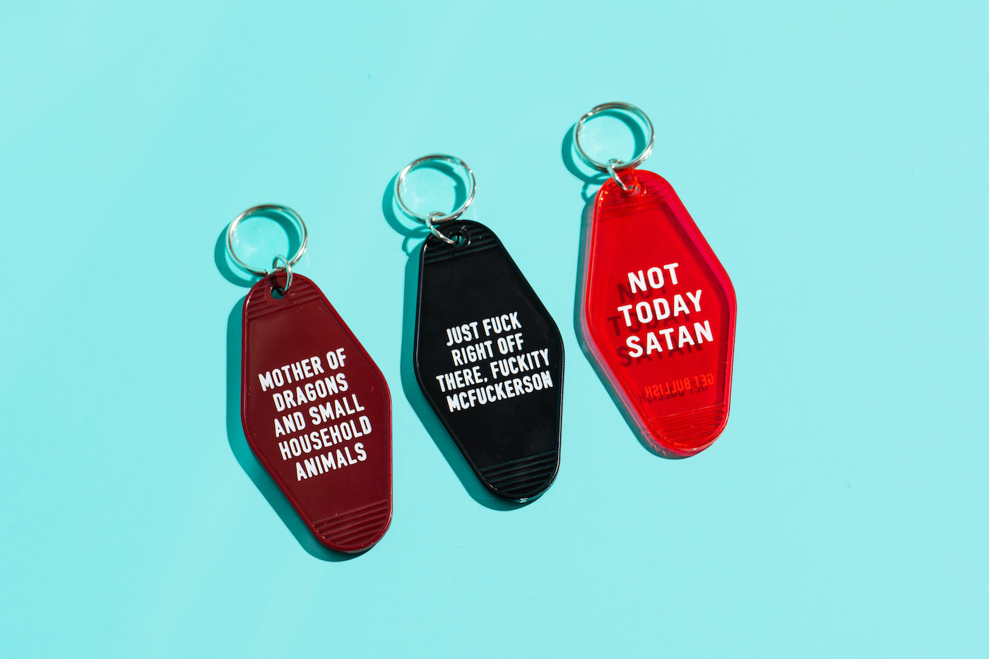 Dark red motel style keychain with white lettering reading 'MOTHER OF DRAGONS AND SMALL HOUSEHOLD ANIMALS', featuring a split ring.