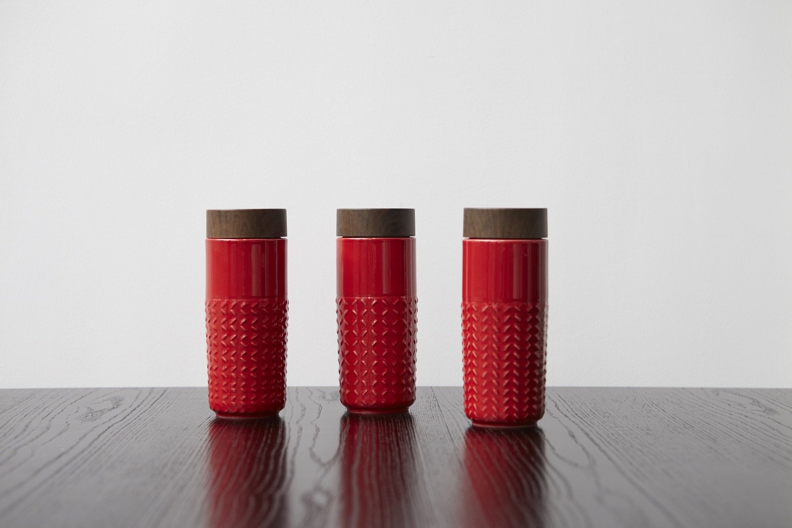 One-O-One Free Soaring Ceramic Tumbler showcasing its elegant design with raised starburst texture and walnut wood-effect lid.