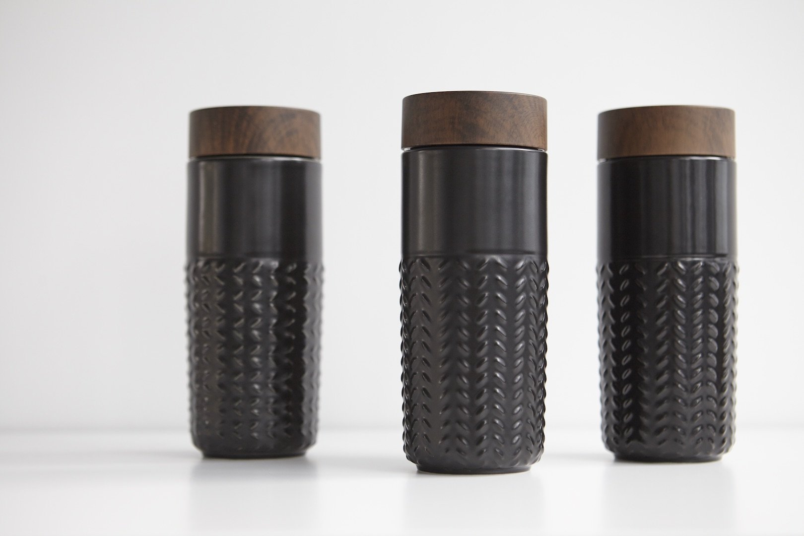 One-O-One Free Soaring Ceramic Tumbler showcasing its elegant design with raised starburst texture and walnut wood-effect lid.