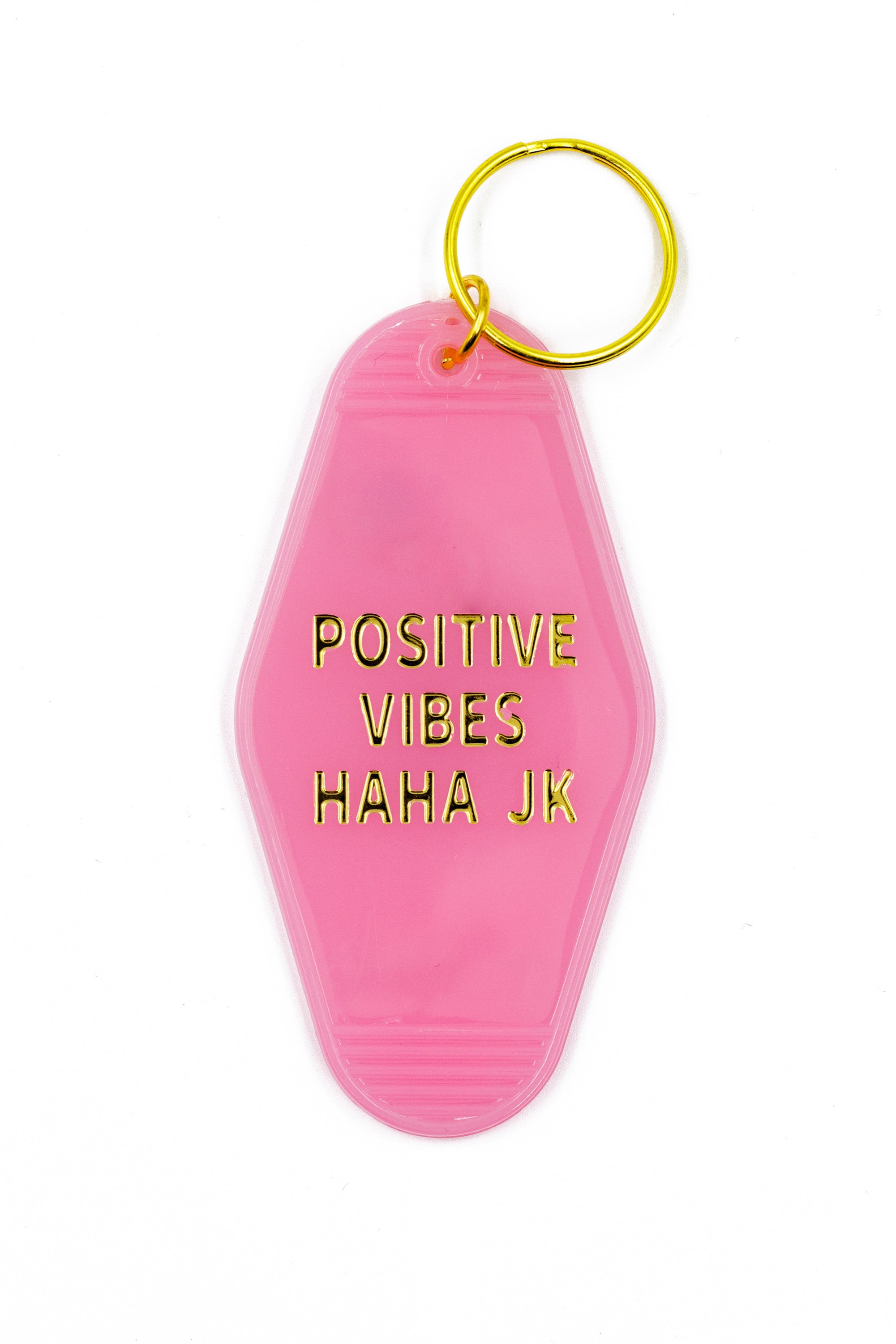 Pink motel keychain with gold lettering reading 'Positive Vibes Haha JK' on the front and 'GET BULLISH' on the back, attached to a brass split ring.