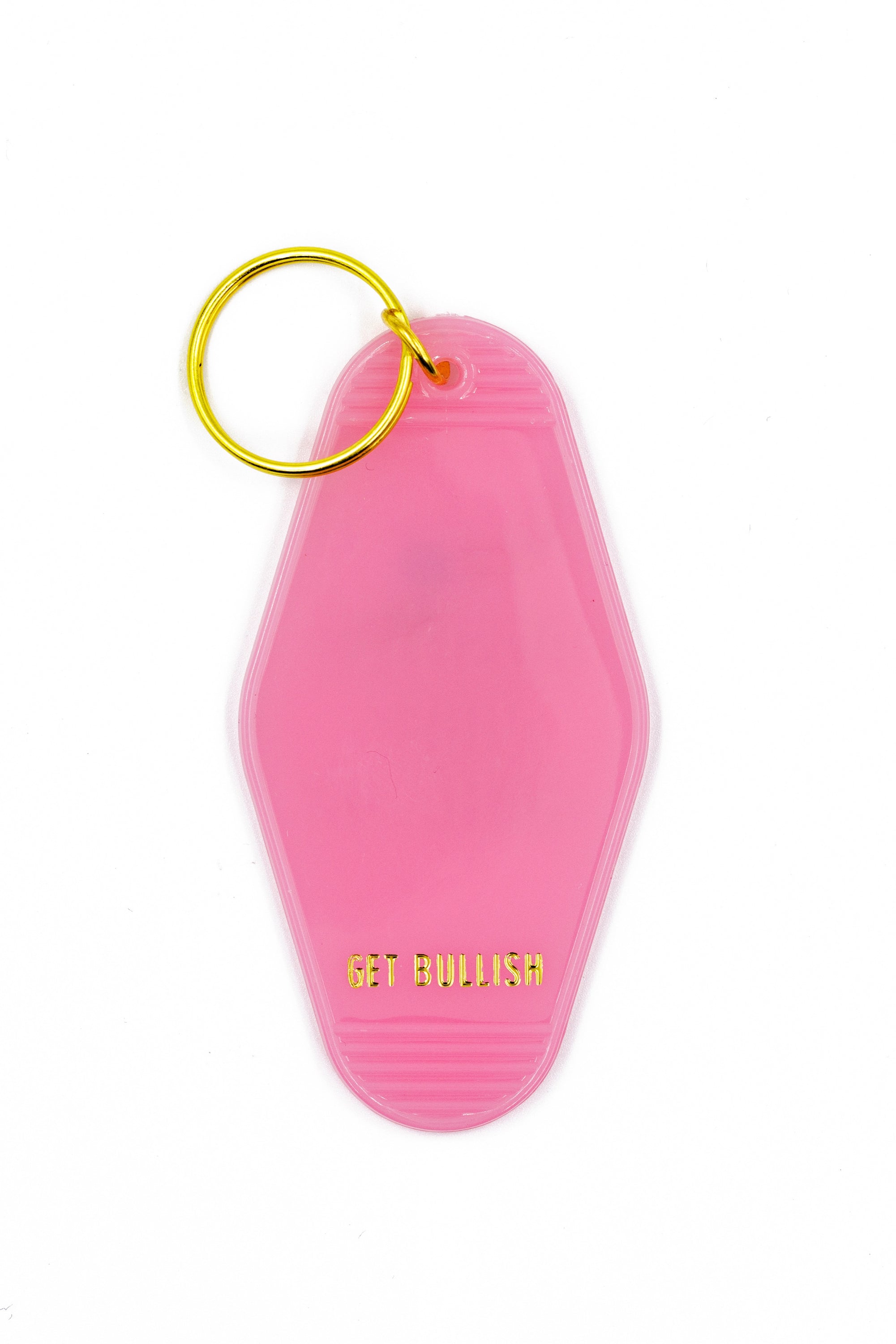 Pink motel keychain with gold lettering reading 'Positive Vibes Haha JK' on the front and 'GET BULLISH' on the back, attached to a brass split ring.