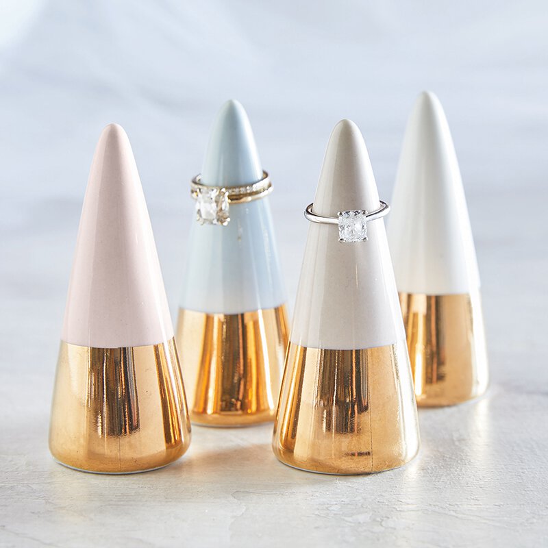 Ceramic ring cone holder in pale grey with a gold metallic bottom, elegantly displaying rings.