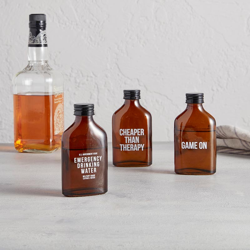 Set of 6 amber glass mini flasks with humorous phrases, perfect for beverages.