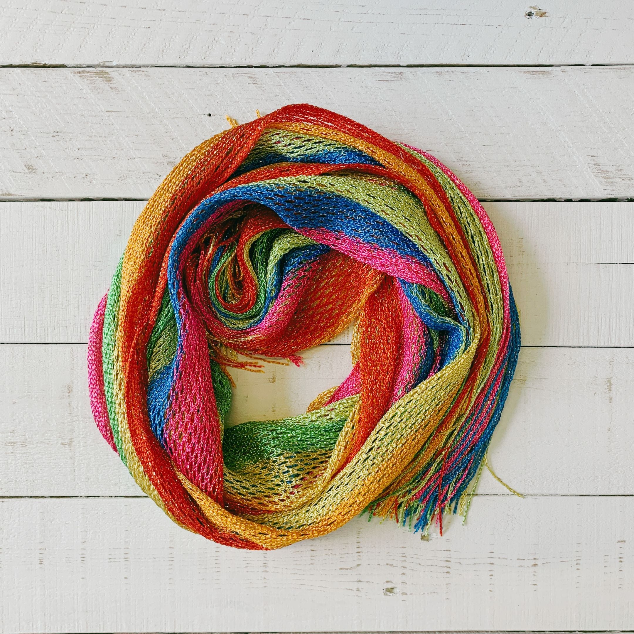 A vibrant Shimmer Mesh Pride Scarf Wrap in Rainbow Stripe, showcasing colorful stripes and a lightweight, shimmering mesh fabric, perfect for summer events.