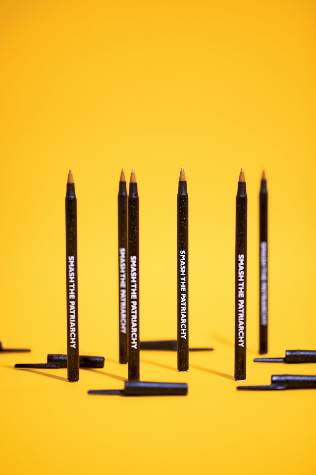 A pack of six black sparkle pens with the phrase 'SMASH THE PATRIARCHY' printed on them, showcasing their stylish design and empowering message.