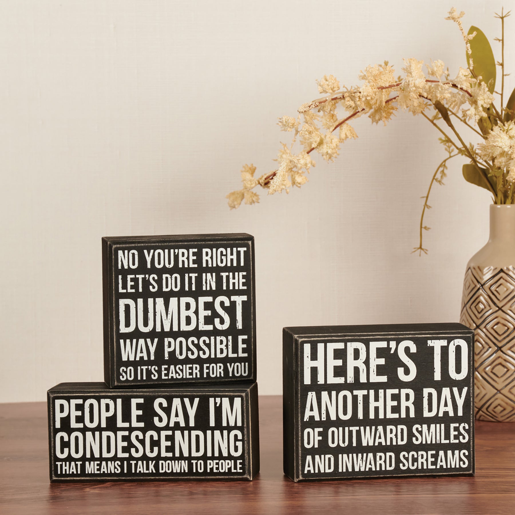 A 4-inch square wooden box sign with a humorous quote in black and white, featuring distressed details and a rustic design.
