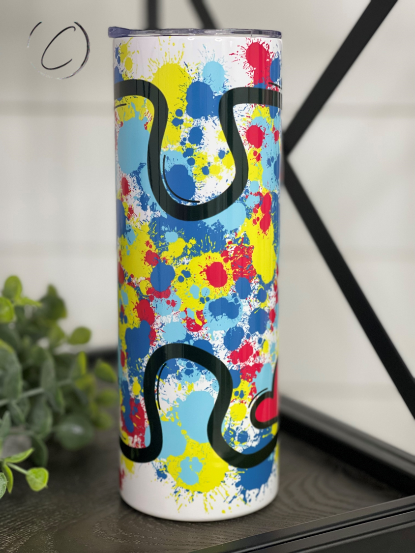 A vibrant 20oz skinny tumbler featuring a splatter design with autism puzzle pieces, perfect for promoting awareness and hydration.