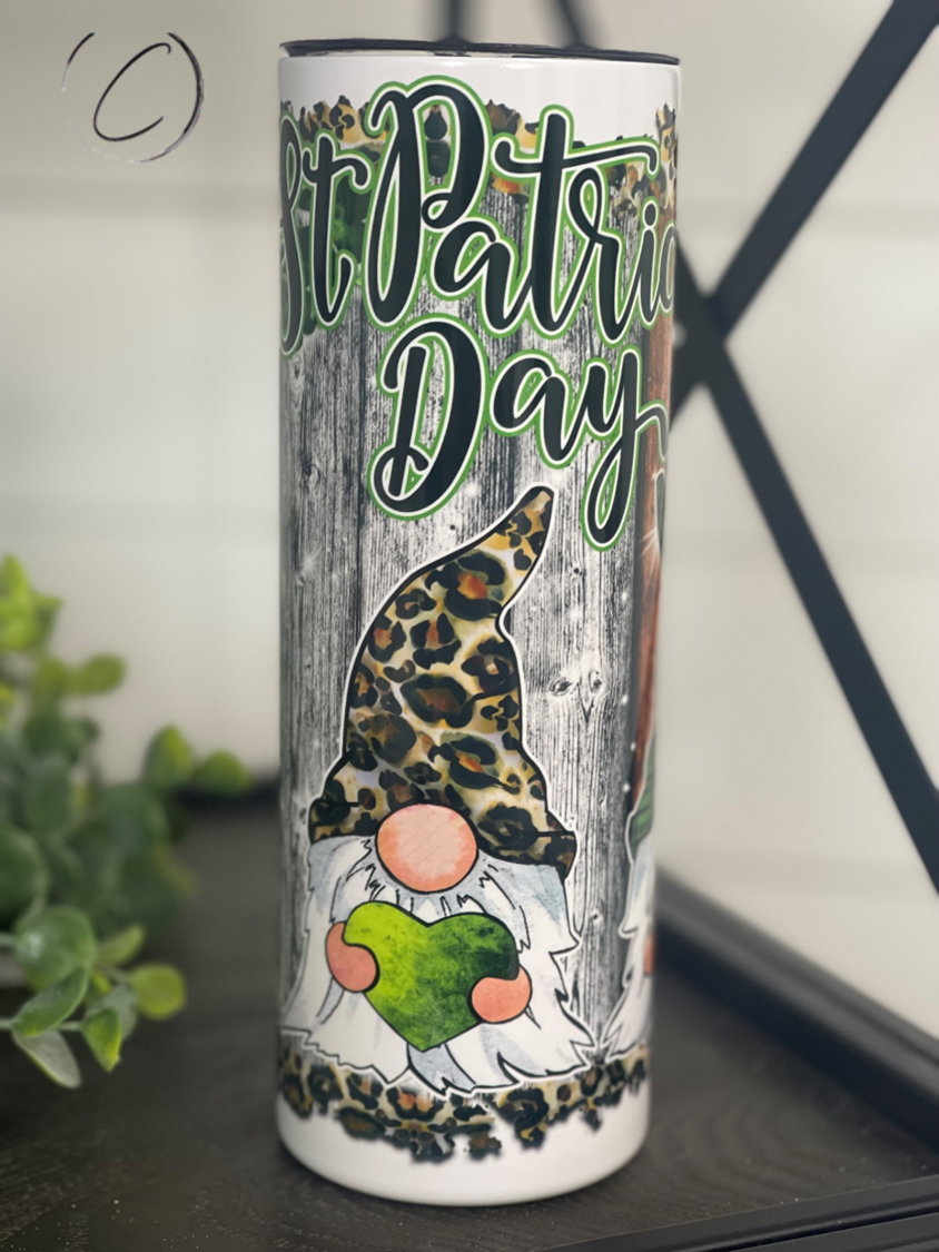A 20oz skinny tumbler featuring festive St. Patrick's Day gnomes, designed for durability and includes a reusable straw.