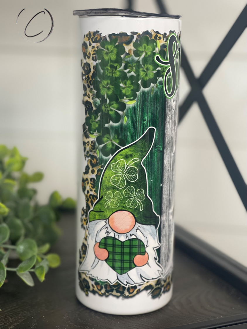 A 20oz skinny tumbler featuring festive St. Patrick's Day gnomes, designed for durability and includes a reusable straw.