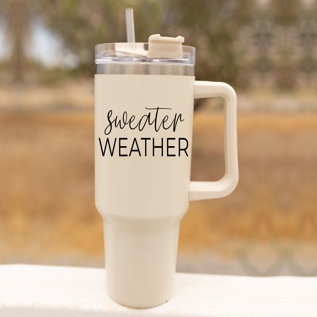 Sweater Weather 40oz Tumbler with cream exterior and black graphic, featuring a handle, lid, and straw.