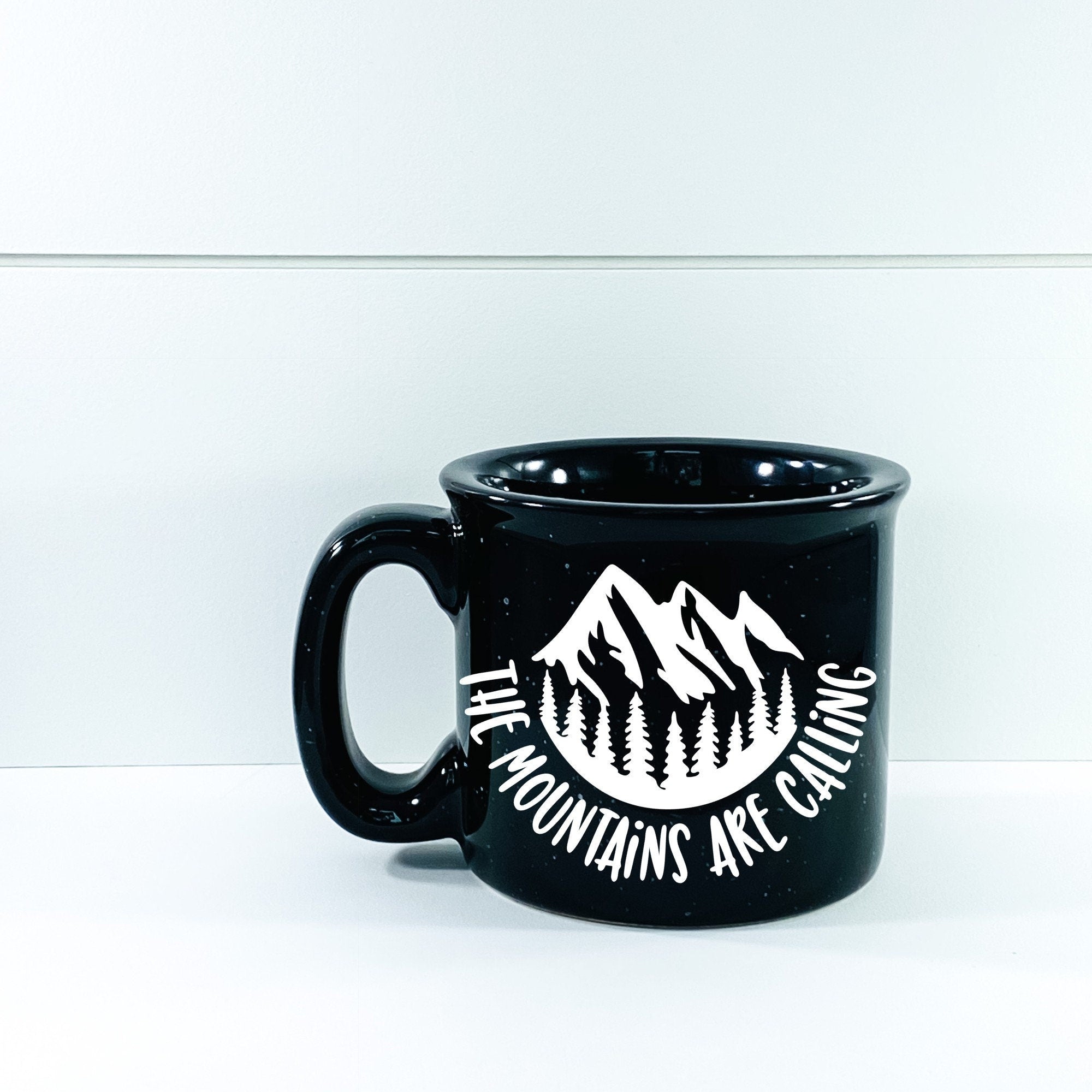 Ceramic campfire mug with 'The Mountains Are Calling And I Must Go' design, perfect for outdoor enthusiasts.