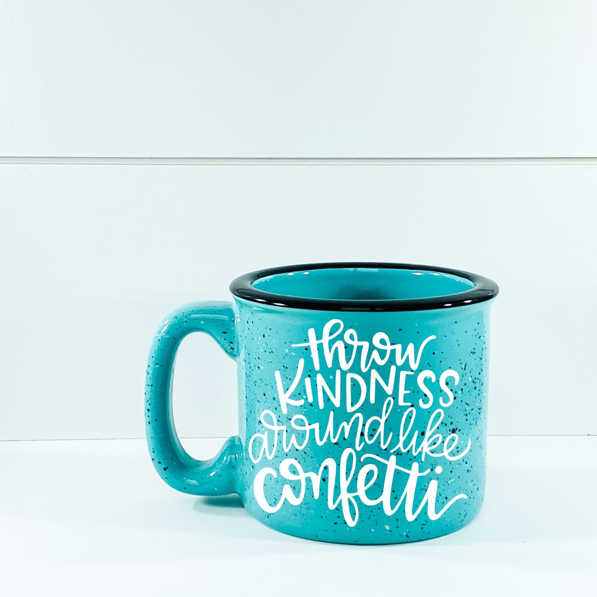 Ceramic campfire mug with 'Throw Kindness Around Like Confetti' design, perfect for cozy beverages.