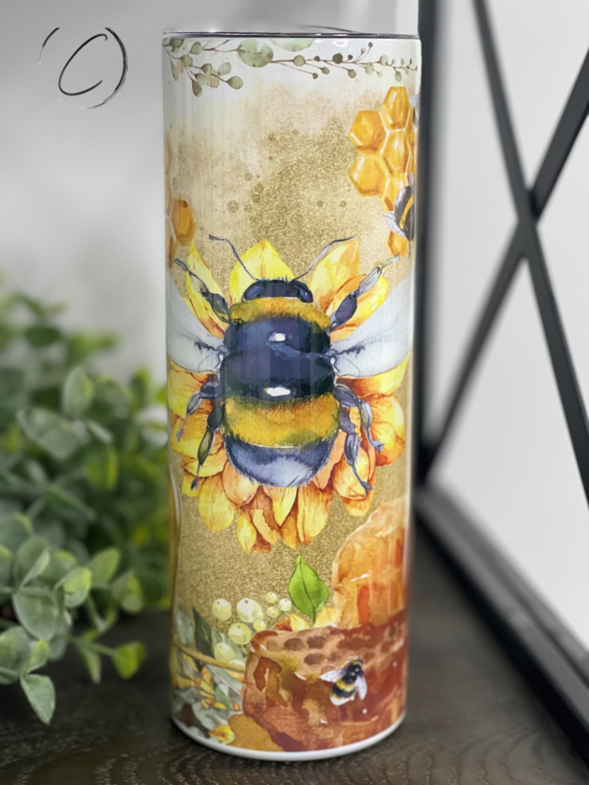 A stylish 20oz skinny tumbler featuring a watercolor honey bee design, perfect for hot and cold beverages.
