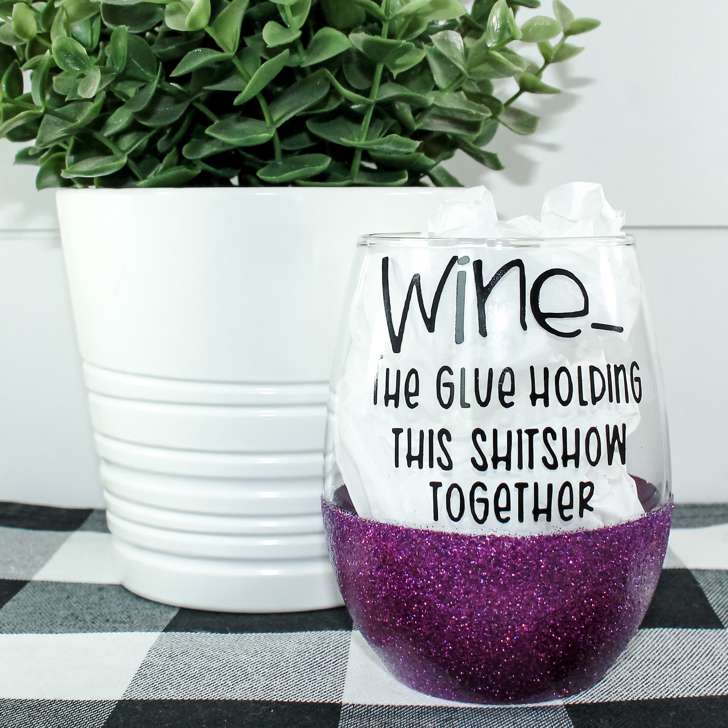 A beautiful stemless wine glass adorned with glitter, showcasing a vibrant design on one side.