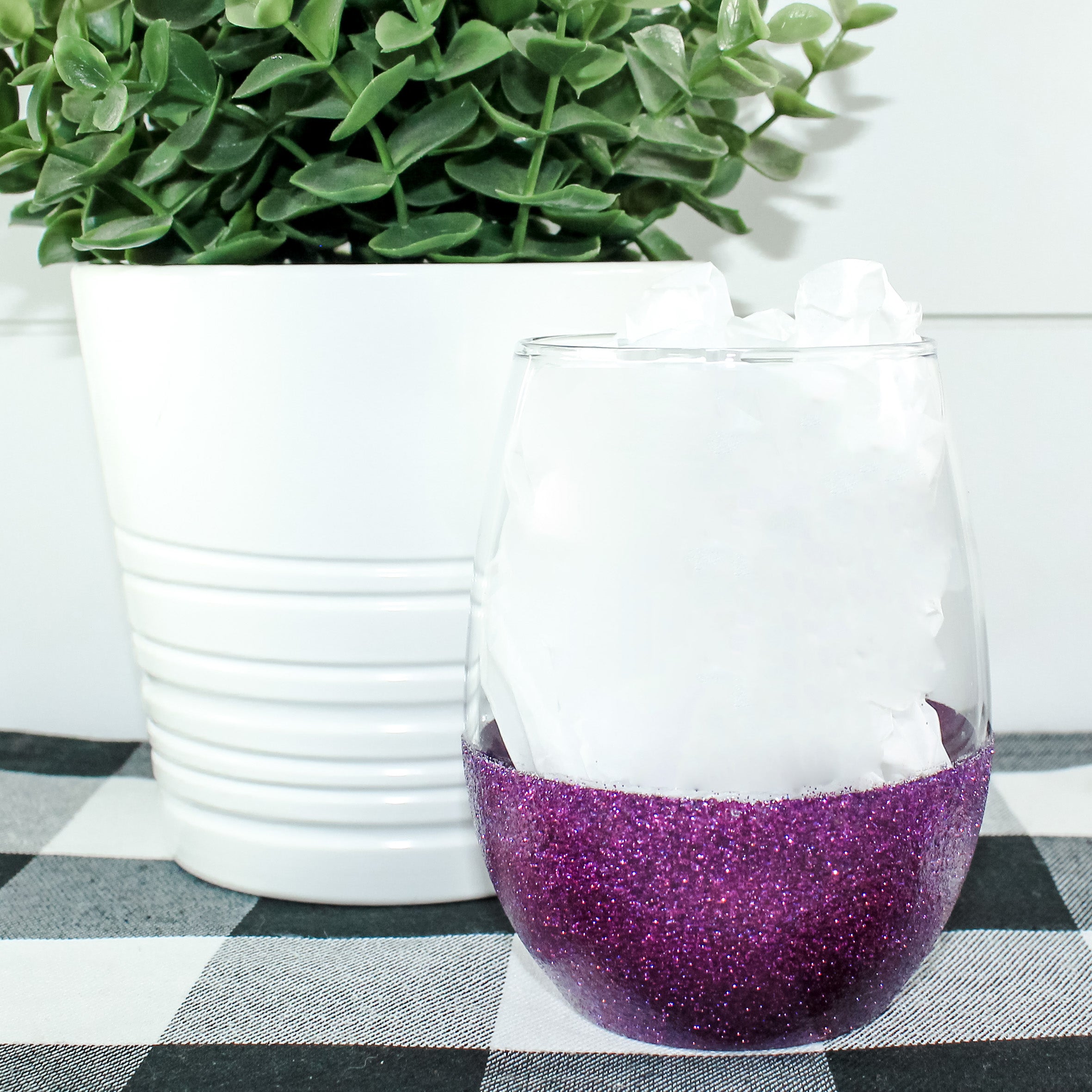 A beautiful stemless wine glass adorned with glitter, showcasing a vibrant design on one side.