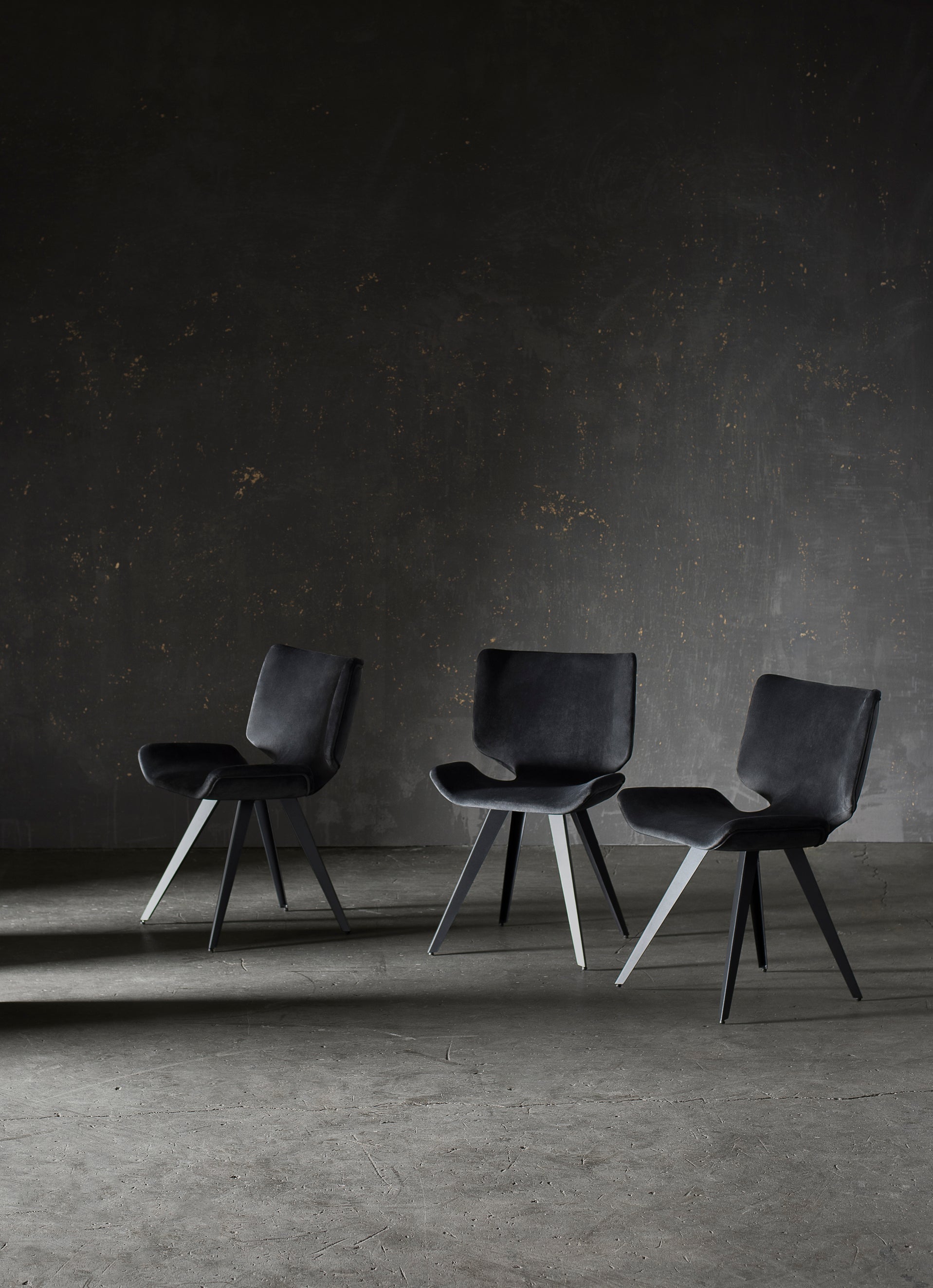 Astra Dining Chair in Shadow Grey with sculptural design and titanium steel legs, showcasing its elegant upholstery and comfortable winged shape.