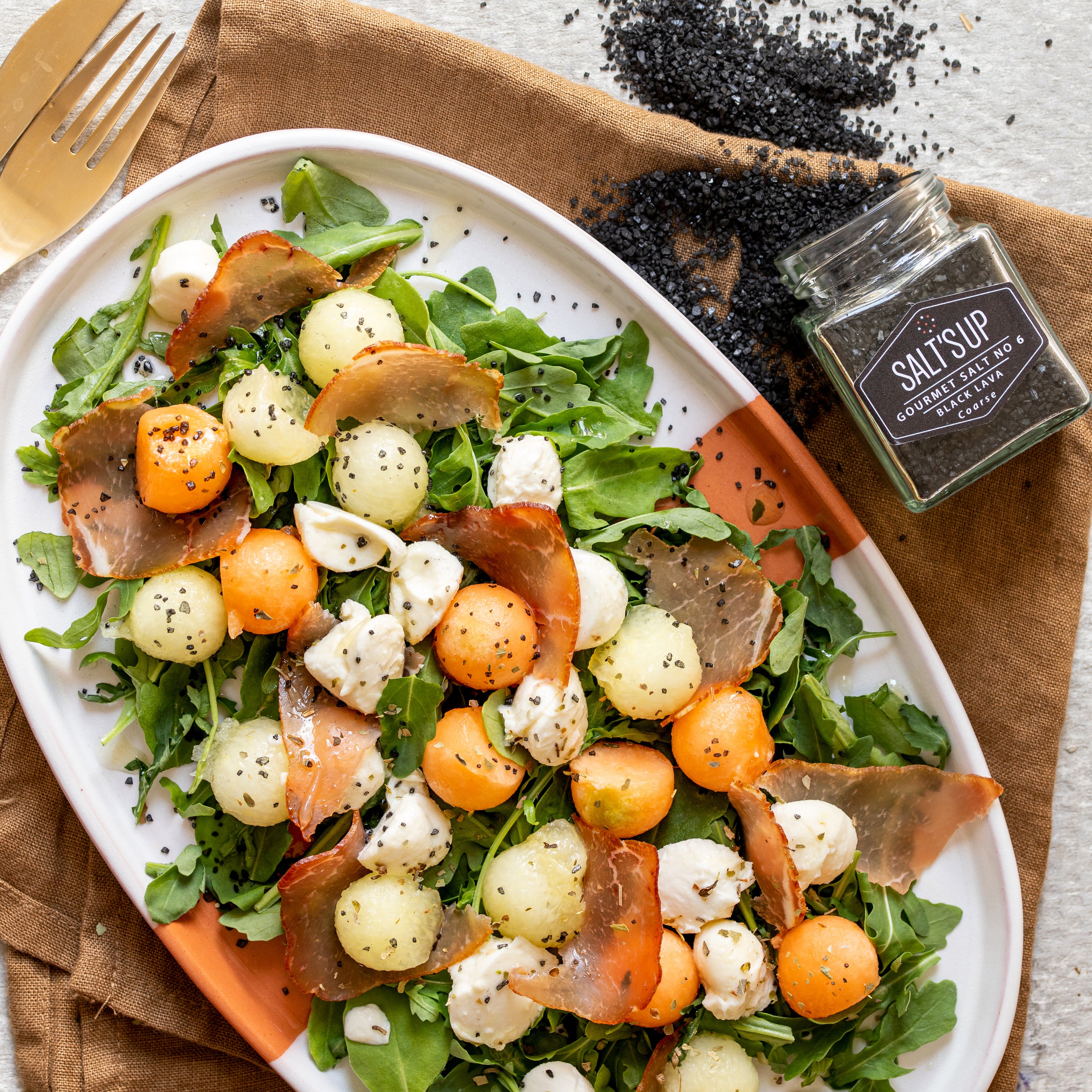 A jar of BLACK LAVA coarse salt showcasing its striking black color and coarse texture, ideal for gourmet cooking.