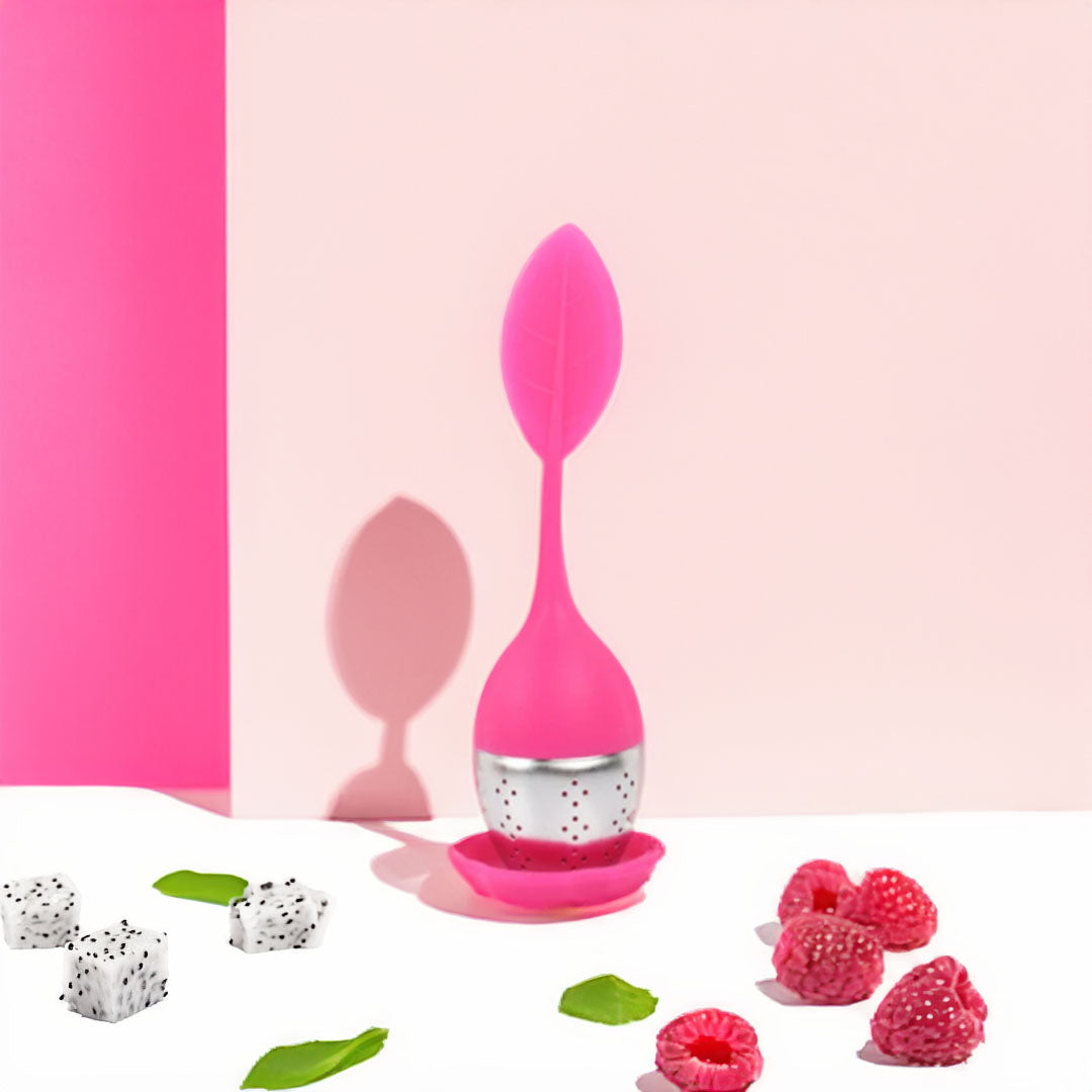 Boule à thé en silicone colorée avec un design moderne, remplie de thé en vrac, posée sur un support.