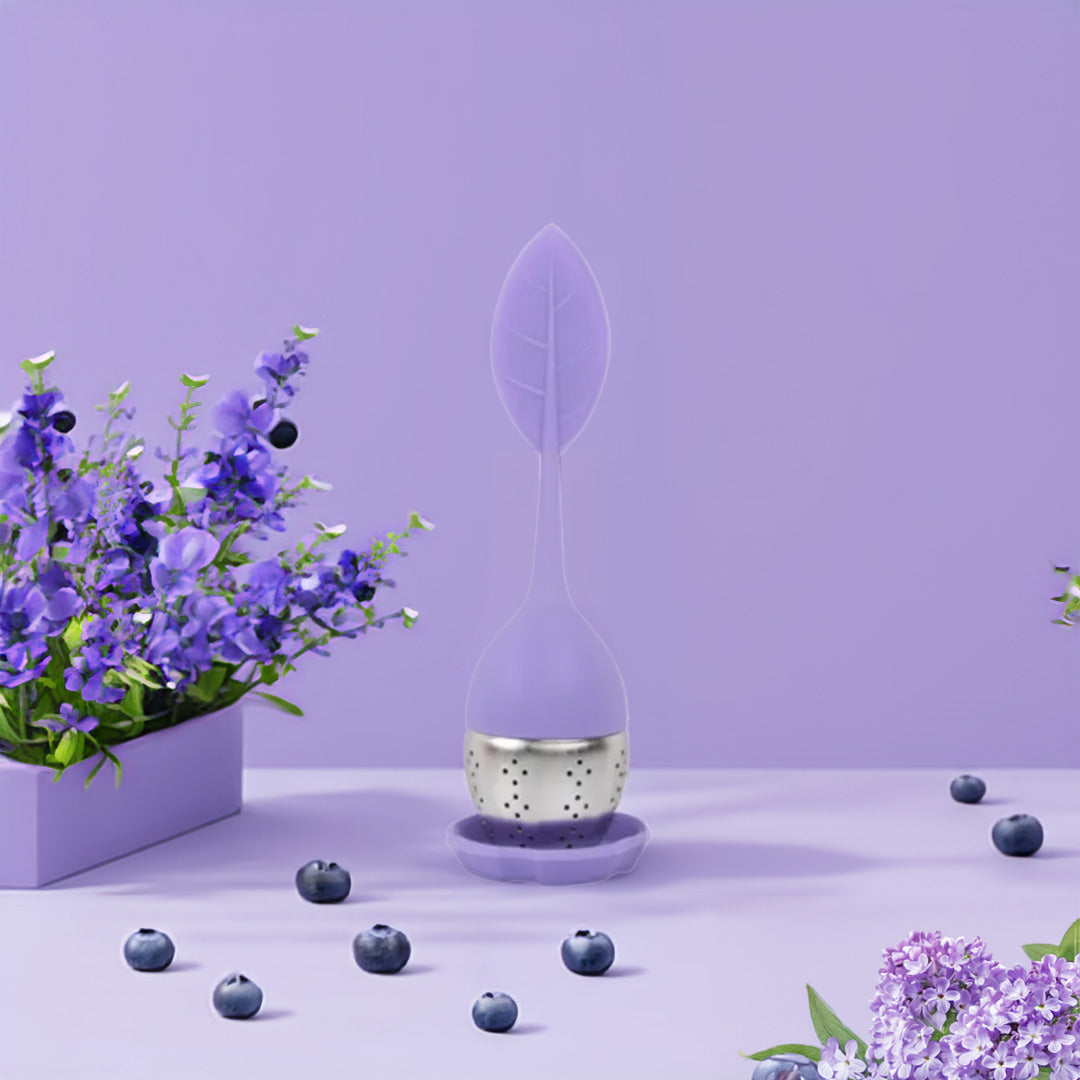 Boule à thé en silicone colorée avec un design moderne, remplie de thé en vrac, posée sur un support.