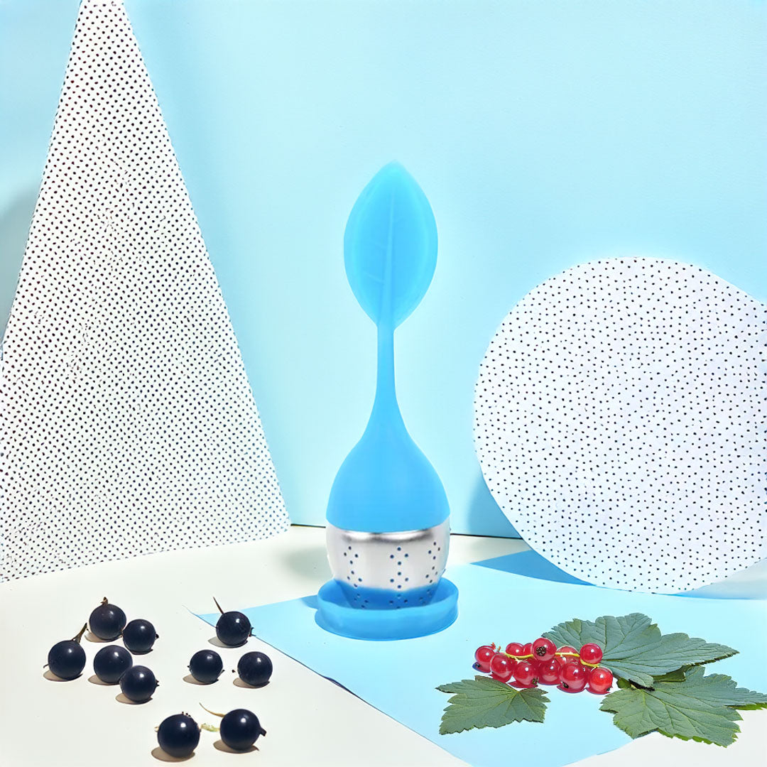 Boule à thé en silicone colorée avec un design moderne, remplie de thé en vrac, posée sur un support.