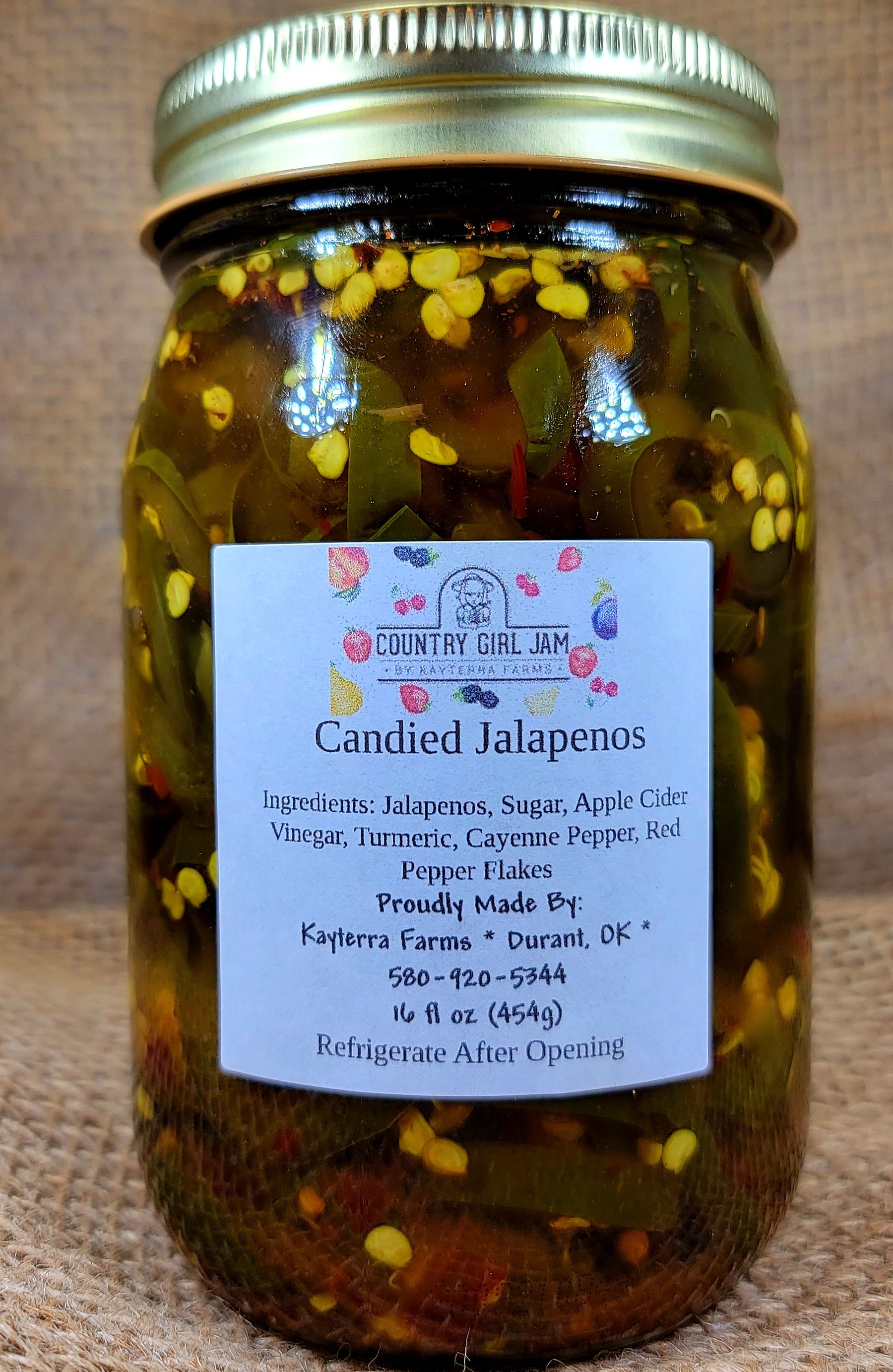 A jar of Candied Jalapenos, showcasing vibrant green jalapeno slices in a sweet syrup, perfect for adding flavor to dishes.