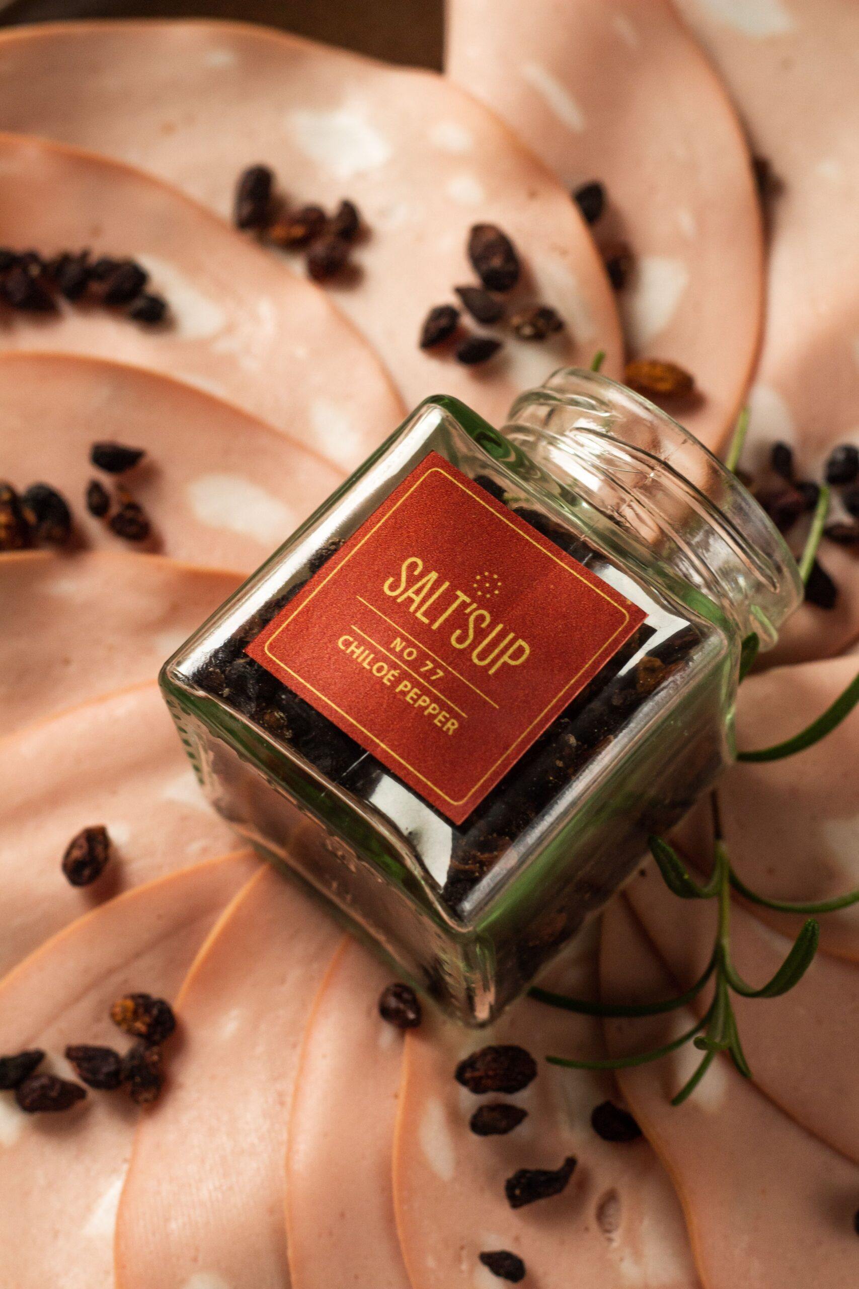 Chiloé pepper in a glass jar, showcasing its unique colors and shape resembling small raisins.