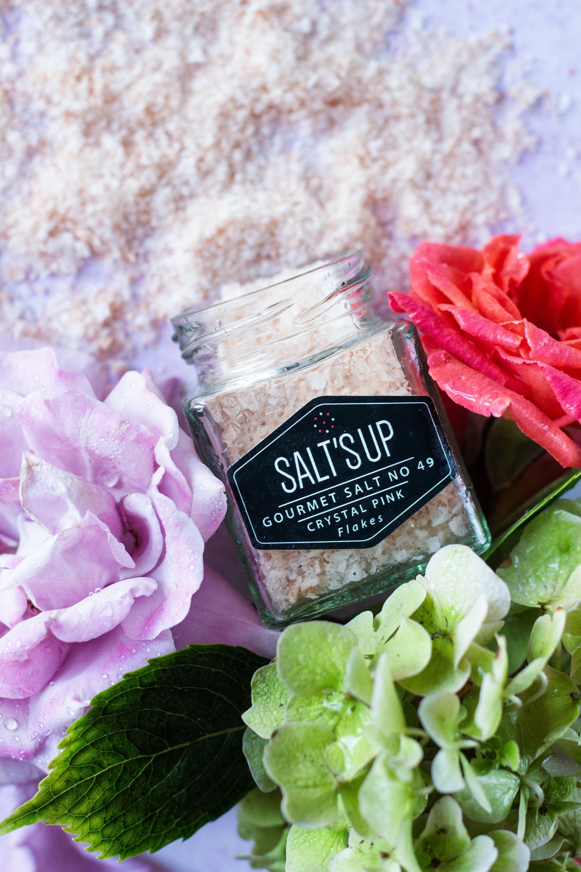 A close-up of CRYSTAL PINK salt flakes in an eco-friendly package, showcasing their pink hue and natural texture.