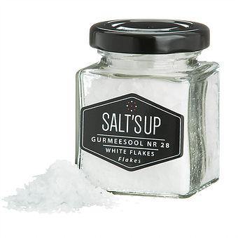 A jar of Cyprus Crystal White salt flakes showcasing large pyramid-shaped crystals, ideal for culinary use.
