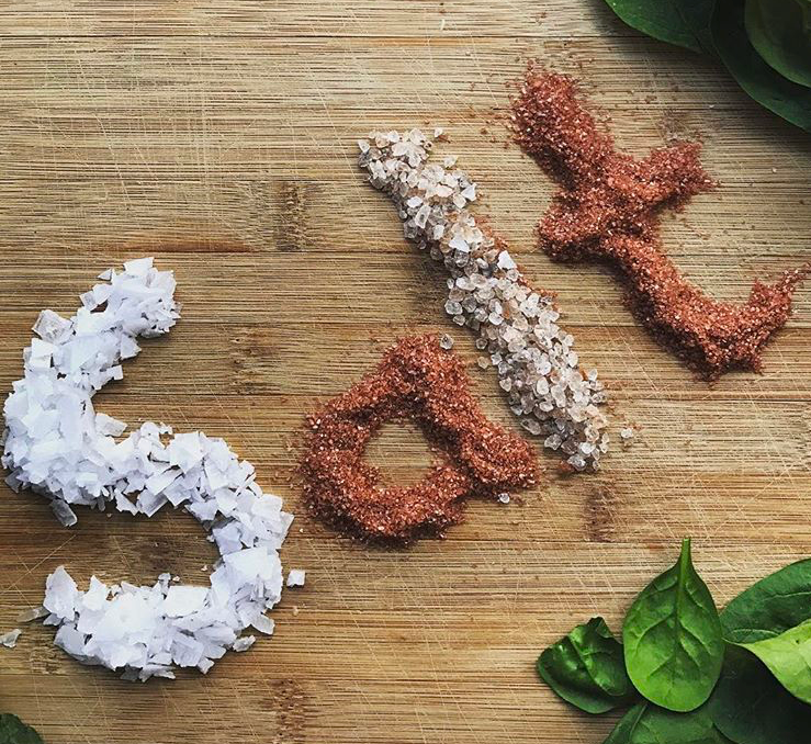 A jar of Cyprus Crystal White salt flakes showcasing large pyramid-shaped crystals, ideal for culinary use.