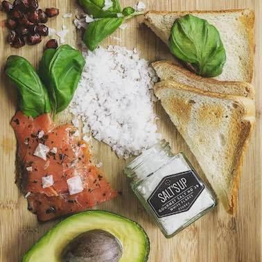A jar of Cyprus Crystal White salt flakes showcasing large pyramid-shaped crystals, ideal for culinary use.