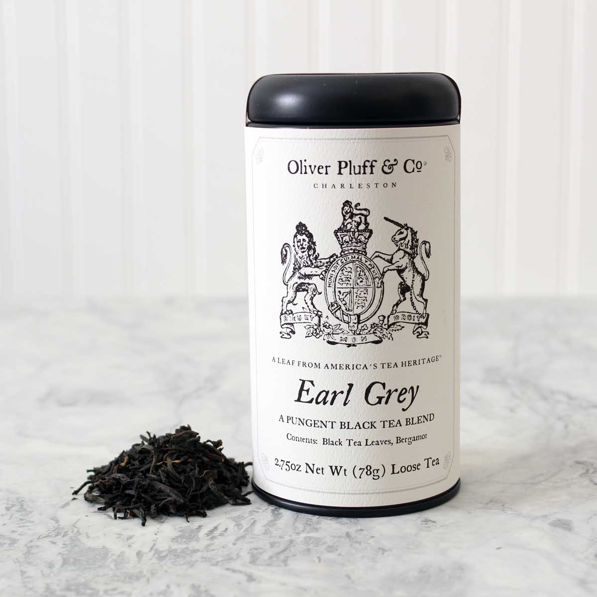 A stylish matte black tin filled with loose Earl Grey Tea, showcasing its elegant packaging and rich aroma.
