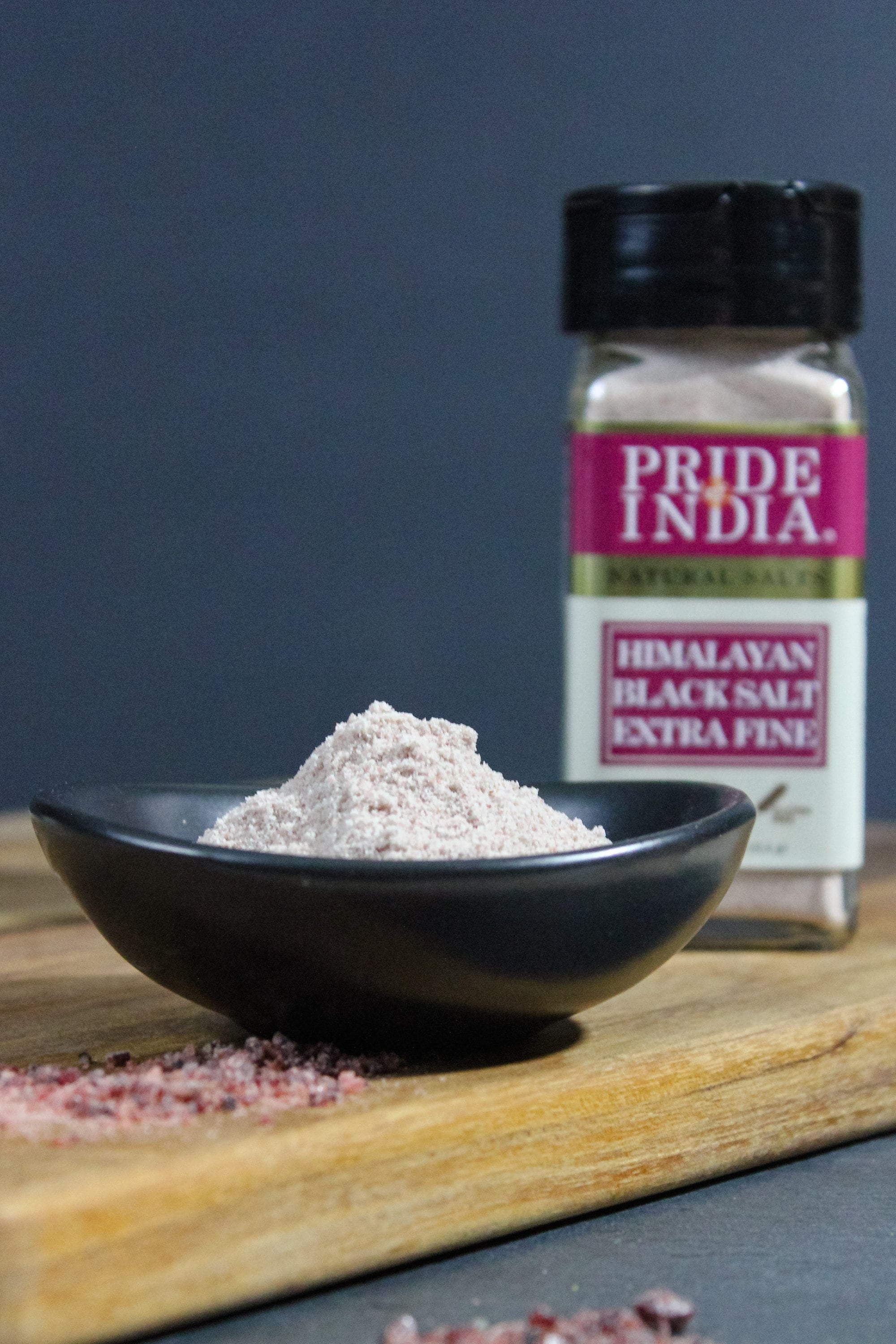 A jar of Pride of India Himalayan Black Rock Salt (Kala Namak) - Extra Fine Grind showcasing its blackish-brown color and fine texture.