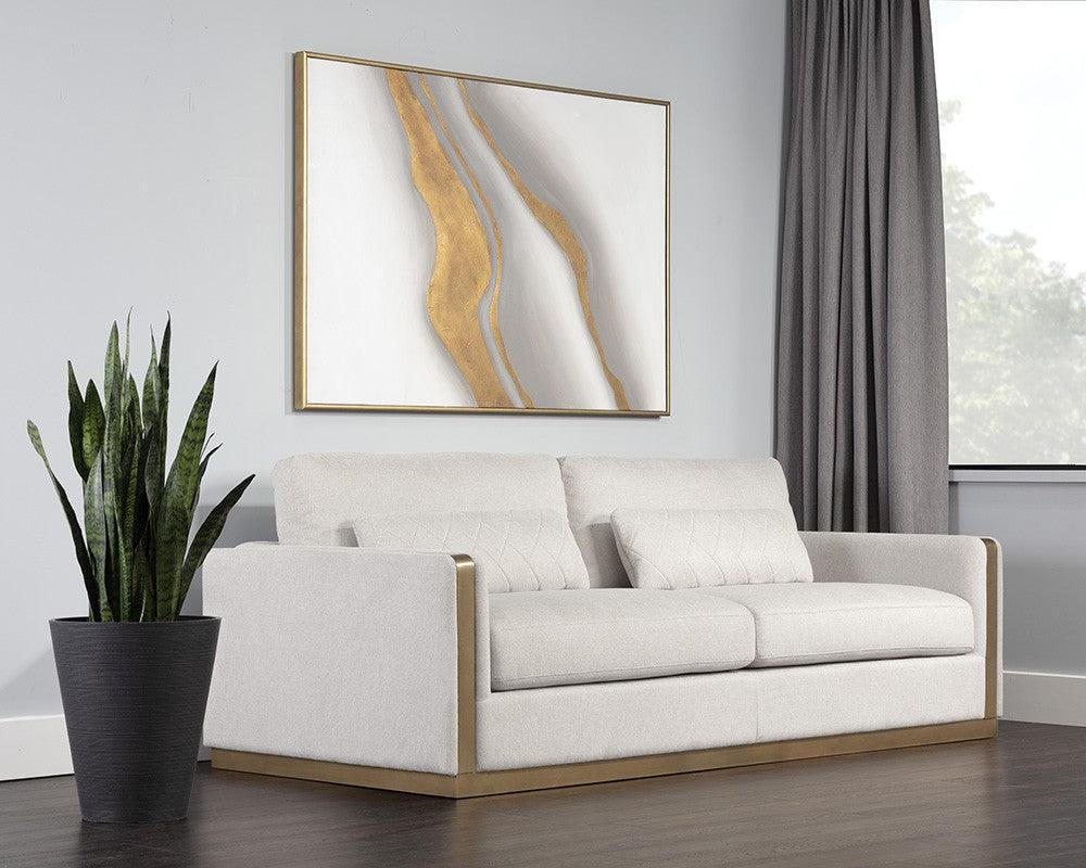 Lean Sofa in Belfast Oatmeal fabric with brass-finished steel legs and quilted pillows, showcasing modern design and comfort.