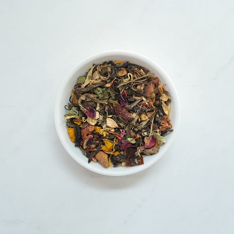 A vibrant package of Recovery: Ginger + Turmeric Pu-erh Blend tea, showcasing its eco-friendly design and colorful ingredients.