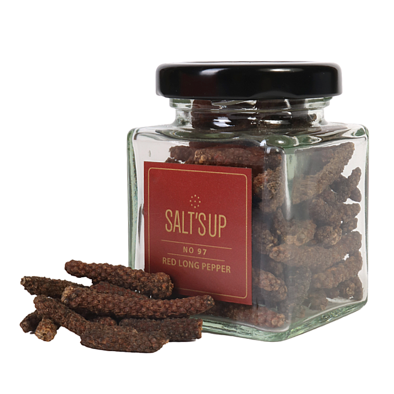 A glass jar filled with vibrant red long pepper, showcasing its unique elongated shape and rich color, perfect for culinary use.