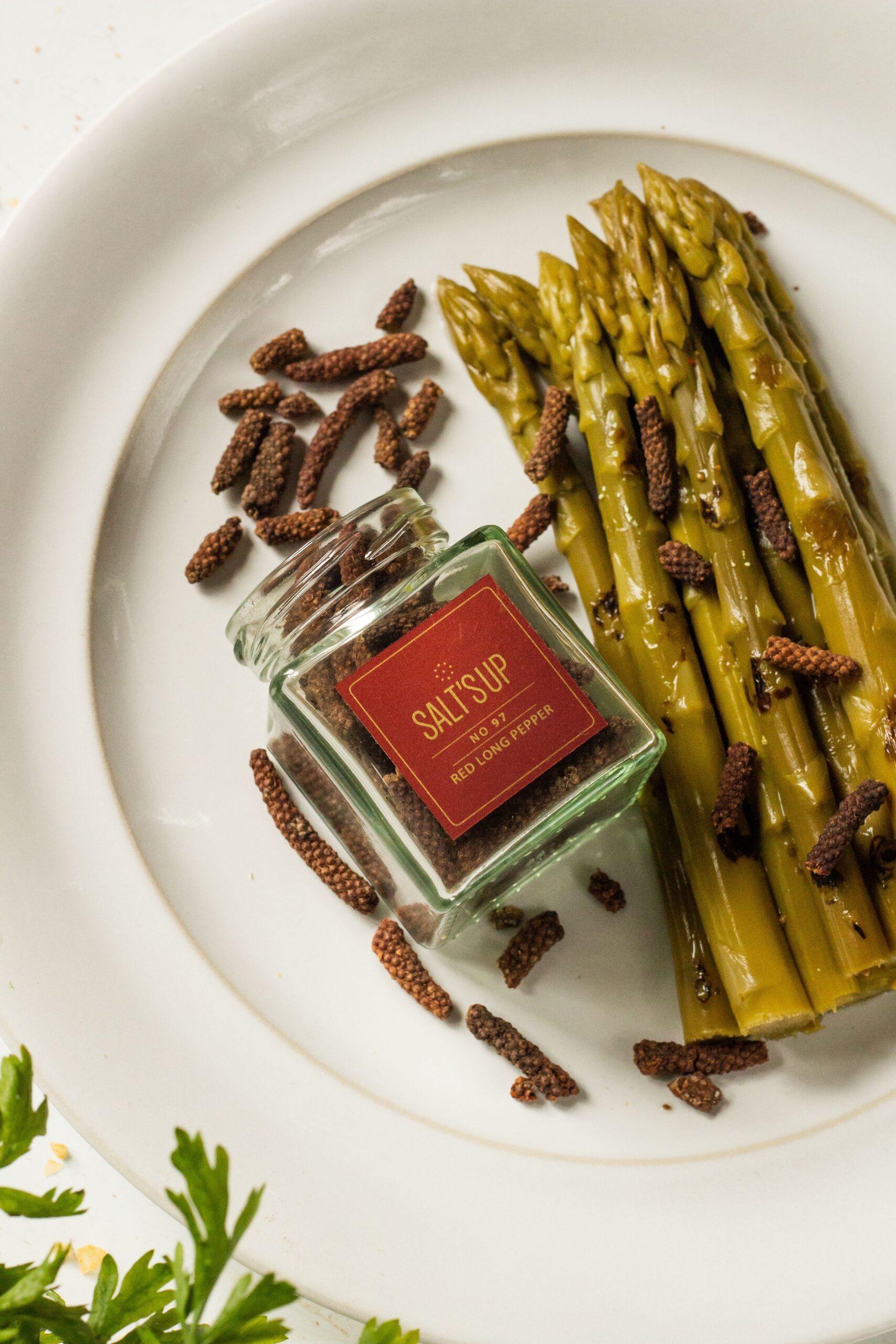 A glass jar filled with vibrant red long pepper, showcasing its unique elongated shape and rich color, perfect for culinary use.