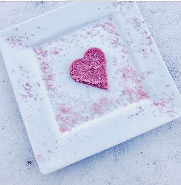 A small glass jar filled with RED WINE gourmet salt, showcasing its fine texture and rich color, with a label indicating its organic and luxurious nature.