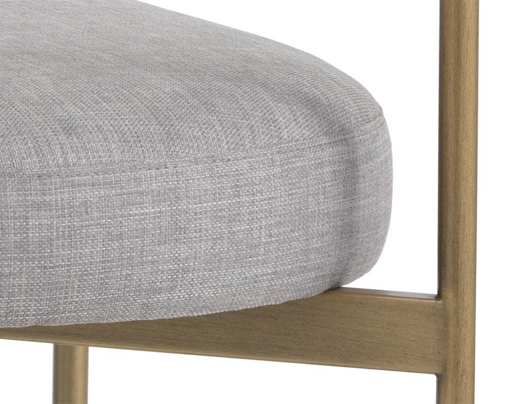 Seneca Dining Chair featuring an antique brass frame and arena cement fabric, showcasing a modern open back design.