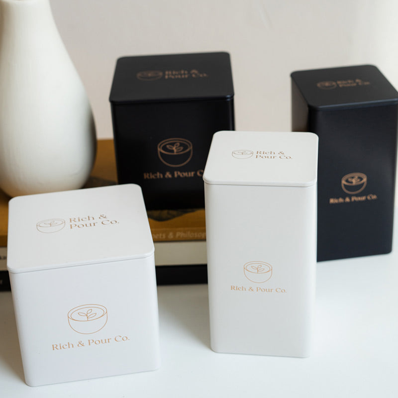 A set of stylish tea storage tins made from recycled steel, available in cubed, tall, and large sizes, showcasing their airtight design.