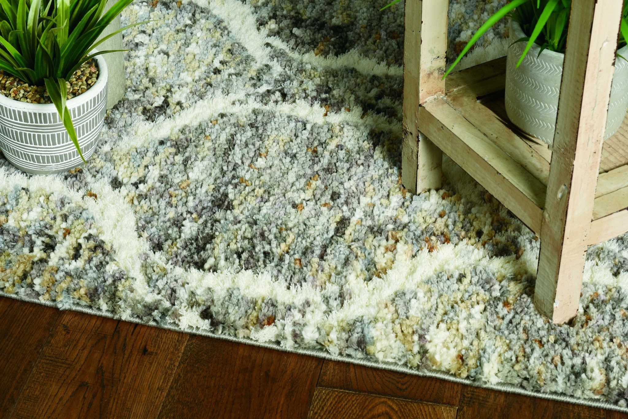 A large 105" X 156" polyester rug in grey and sand colors, featuring a cozy boho design with fringe detailing, perfect for enhancing living spaces.