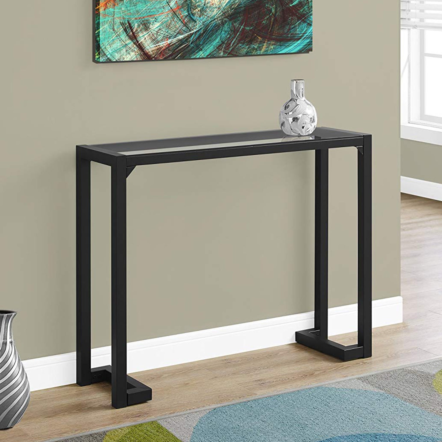 A sleek 12x42x32 tempered glass and black metal accent table, showcasing a modern design suitable for various home decor styles.